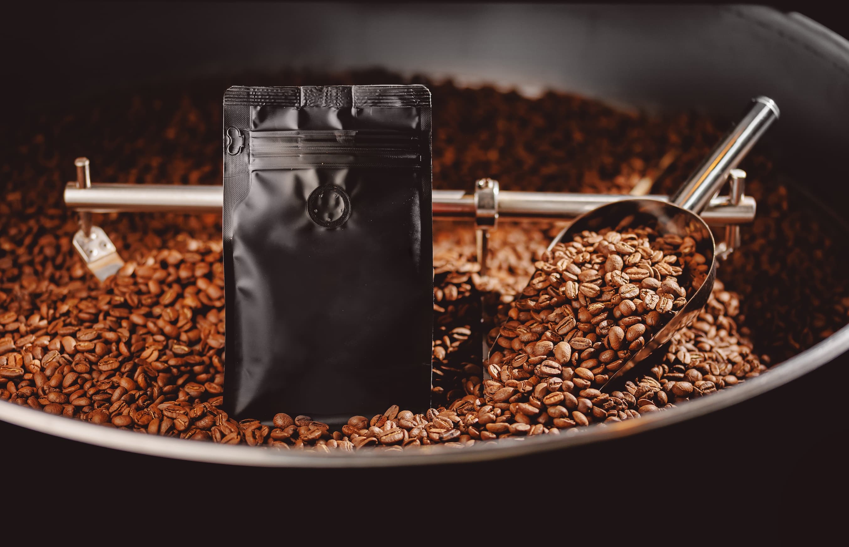 Schwarze Kaffeeverpackung steht zwischen frisch gerösteten Kaffeebohnen.