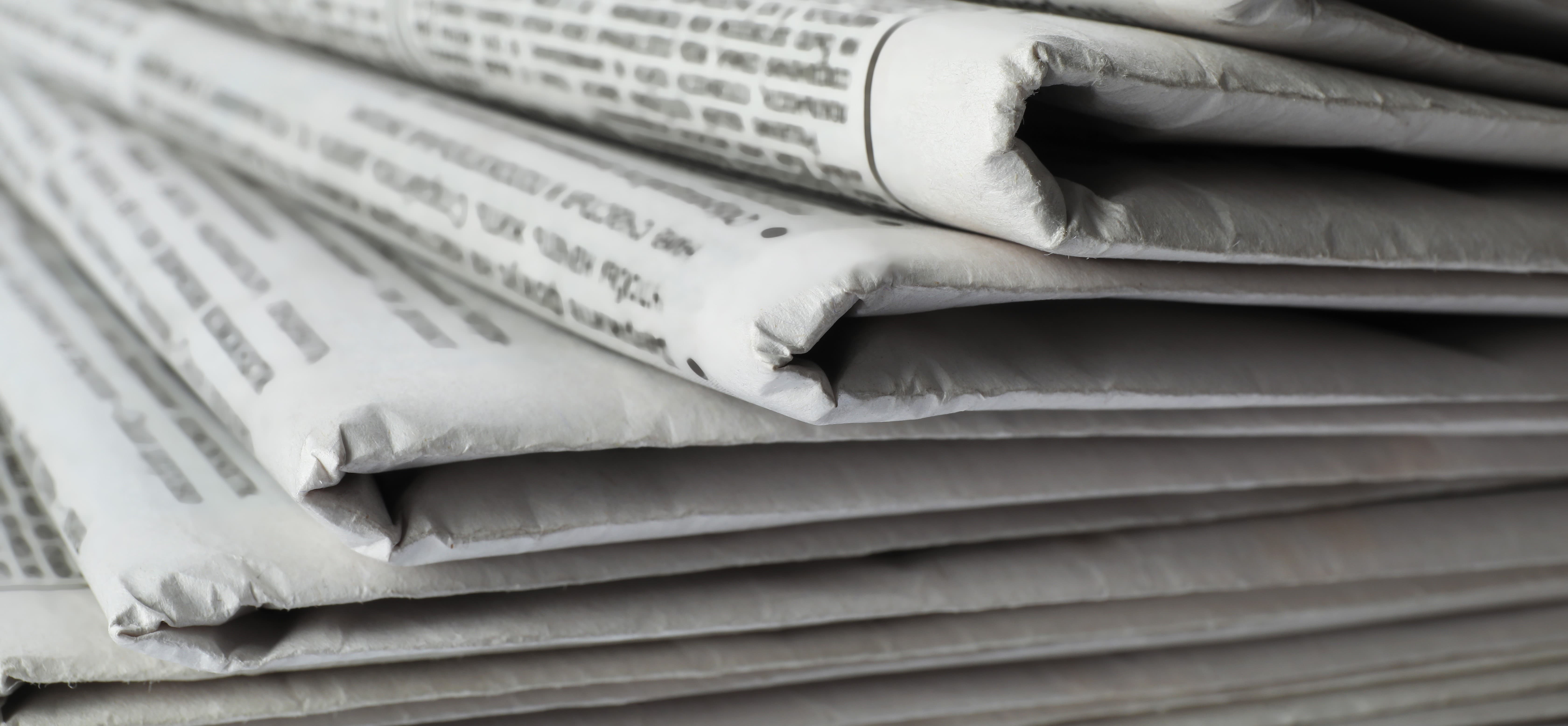 Mehrere gefaltete Zeitungen liegen übereinander gestapelt.