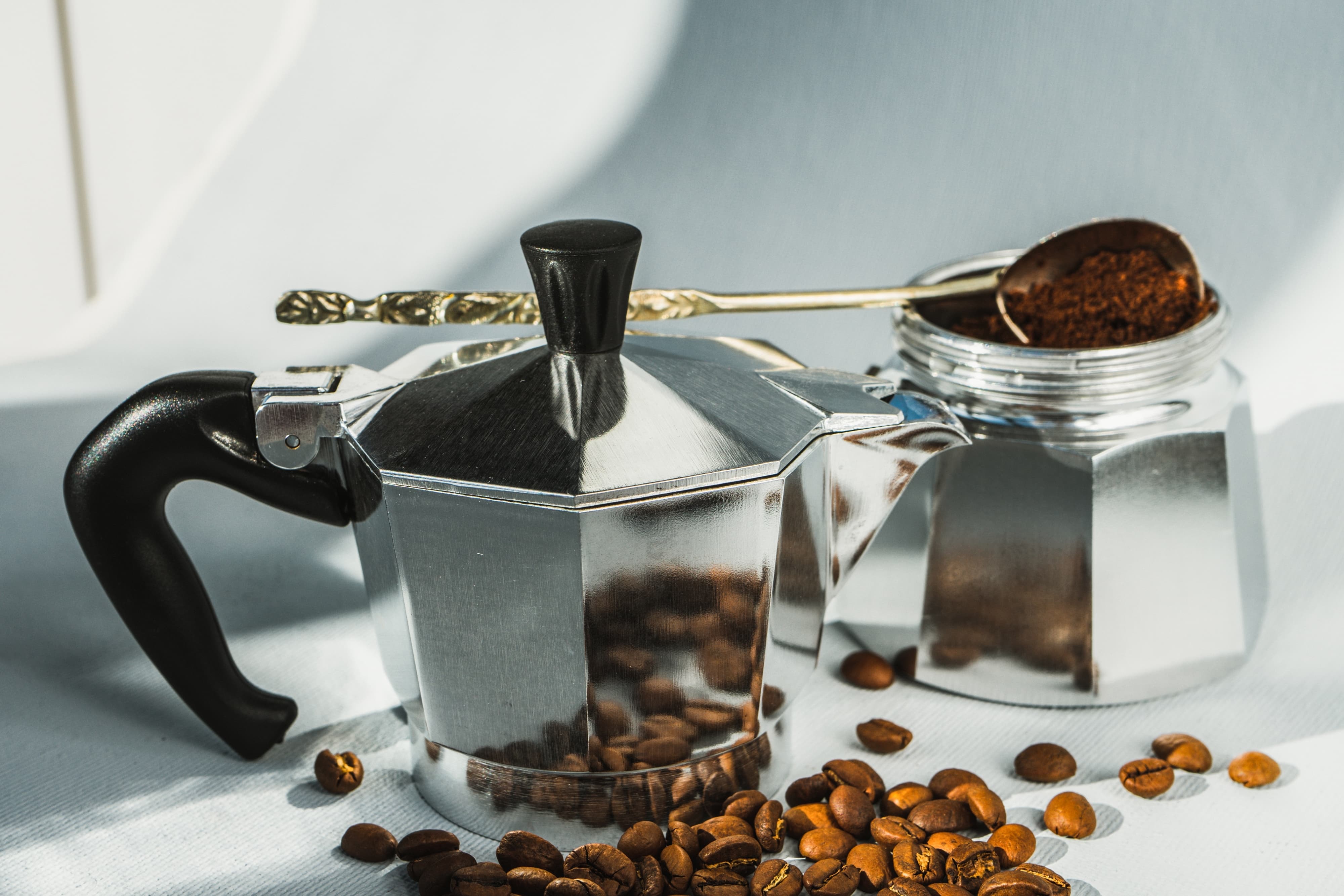 Klassische silberne Mokkakanne mit Kaffeepulver und Kaffeebohnen.