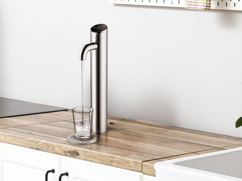 BRITA BR55 Wassserspender mit Edelstahl-Wasserhahn befüllt Glas auf heller Holzarbeitsplatte in Küche.