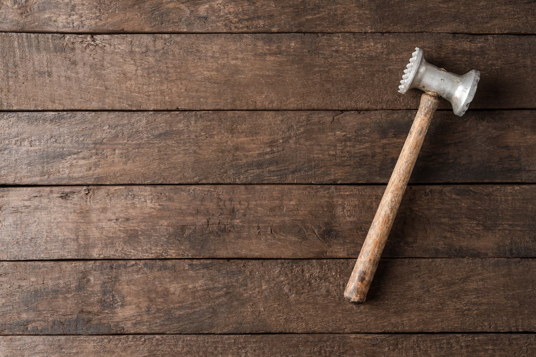 Kuechenholzhammer auf rustikalem braunen Holztisch liegend, Draufsicht.