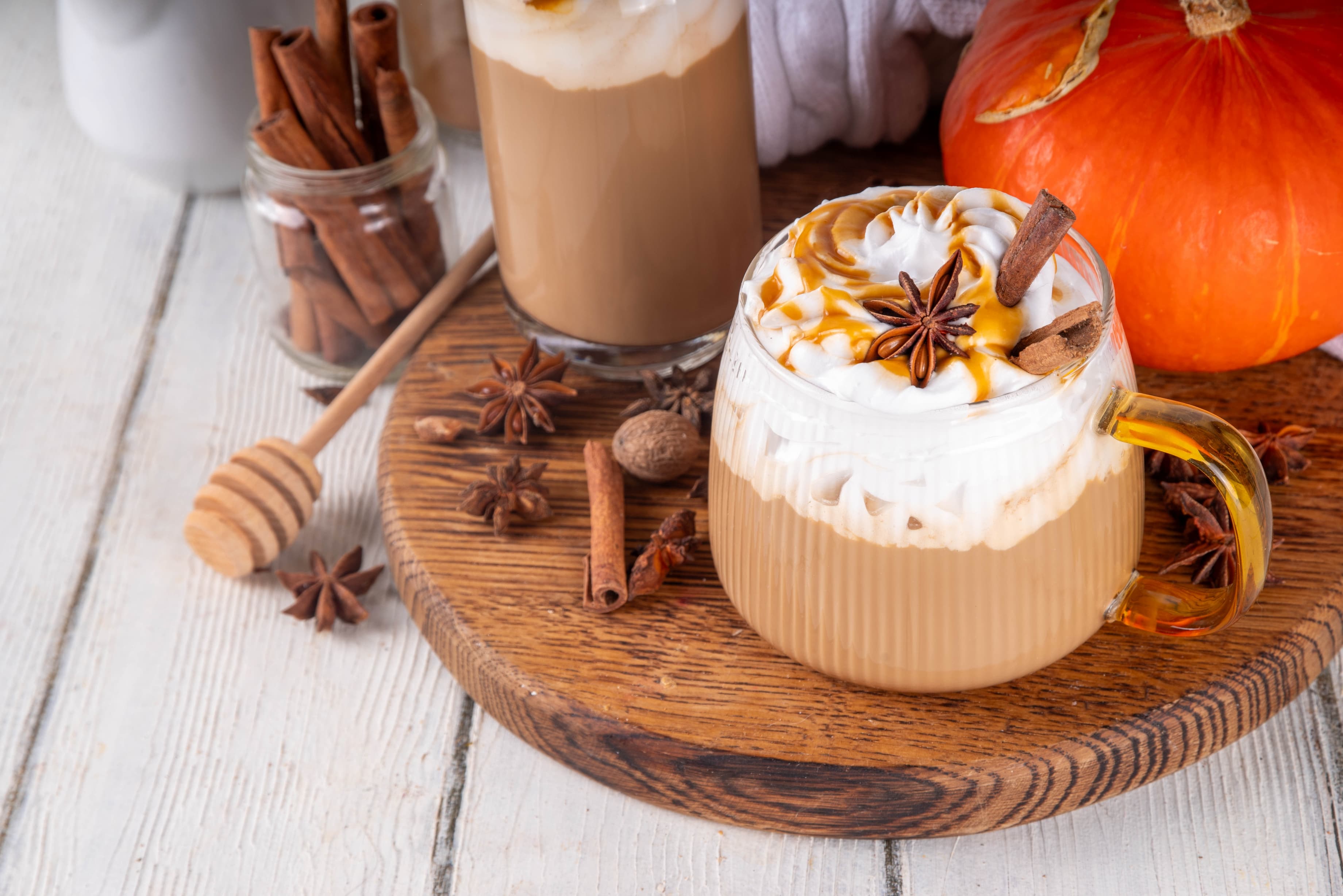 Herbstlicher Pumpkin Spice Latte mit Sahne, Zimt und Kürbisdeko.
