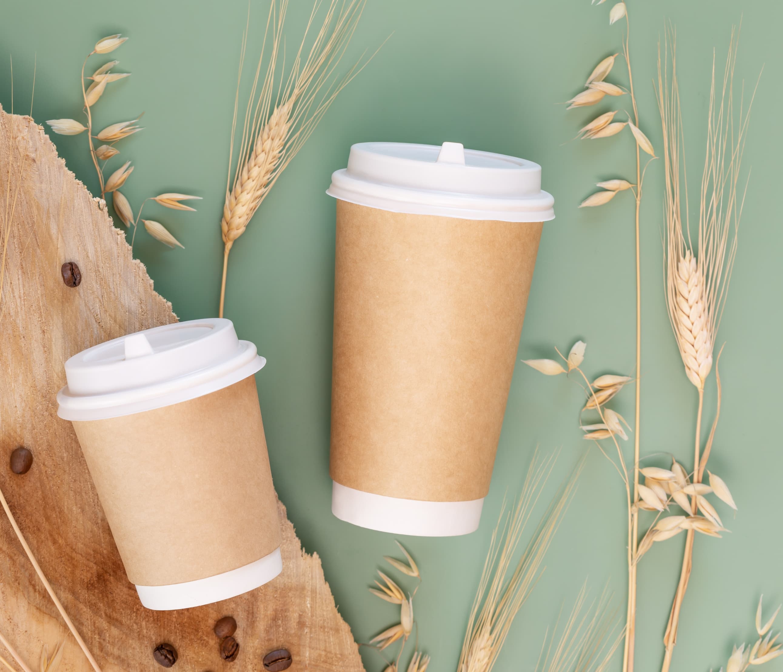 Zwei Kaffeebecher To Go aus braunem Karton mit Deckel, dekoriert mit Getreideähren.