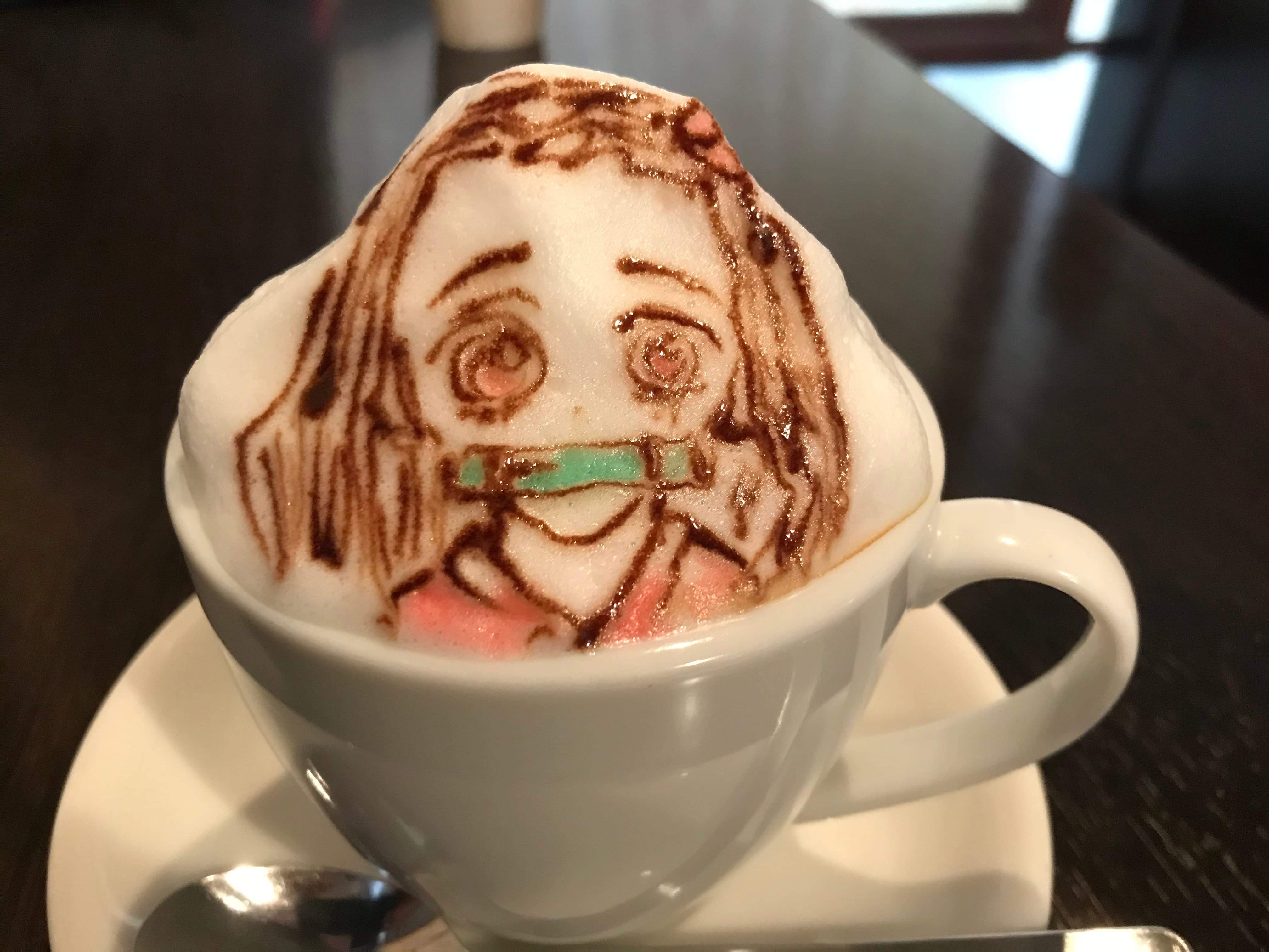 Kaffeetasse mit Milchschaum und kunstvollem Anime-Charakter als Latte Art.
