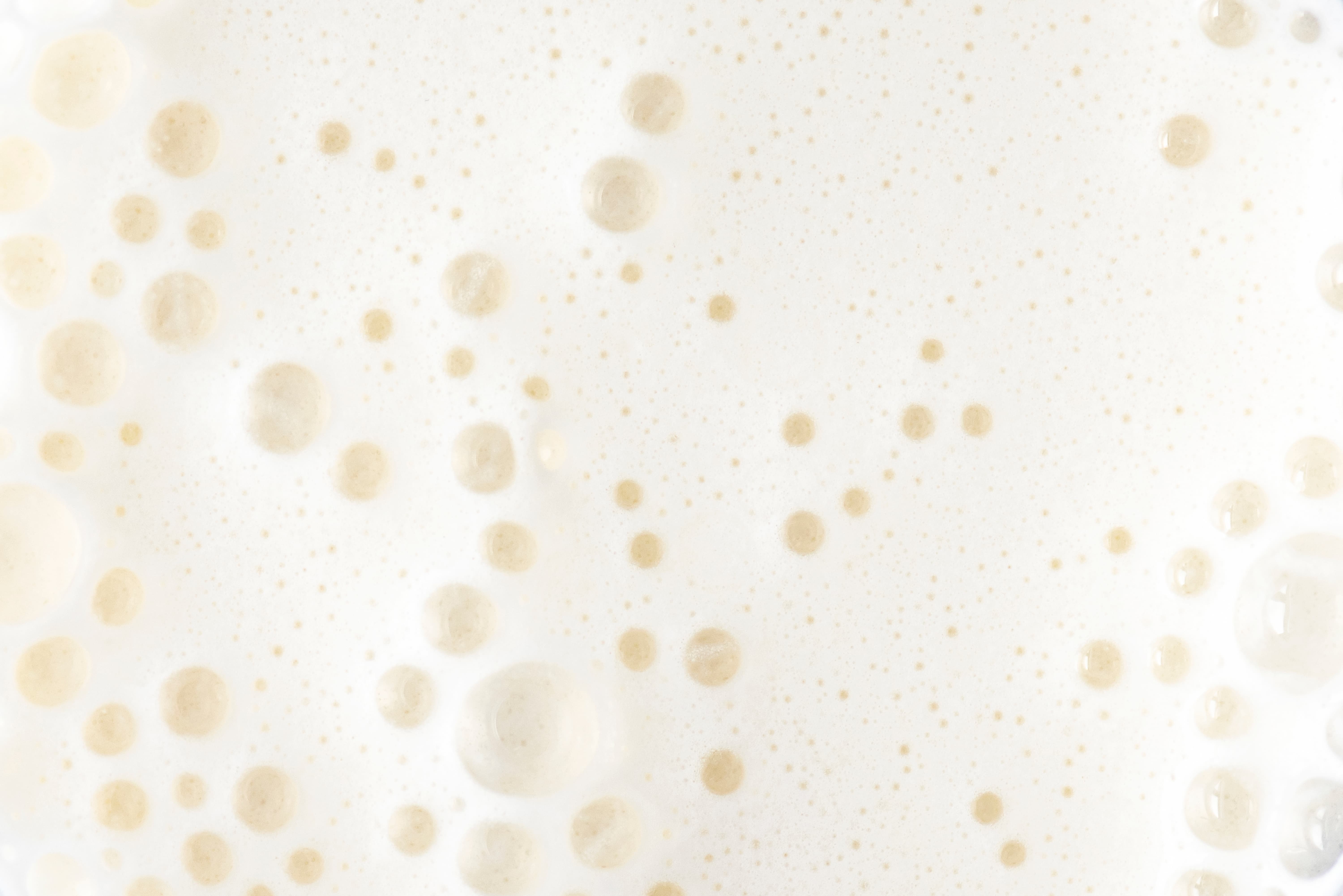 Nahaufnahme von cremigem Milchschaum mit Blasenstruktur.
